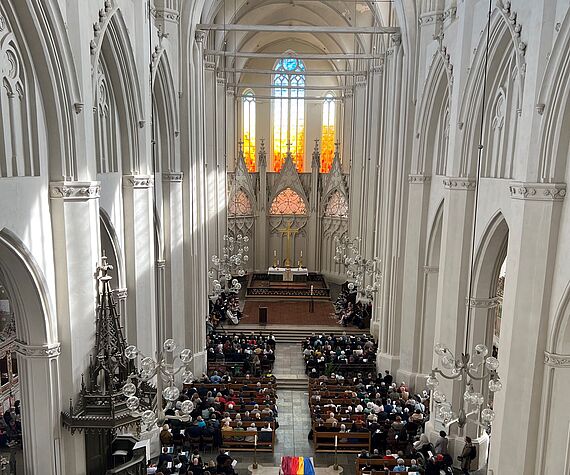 Blick durch den voll besetzten Greifswalder Dom auf die neuen Fenster